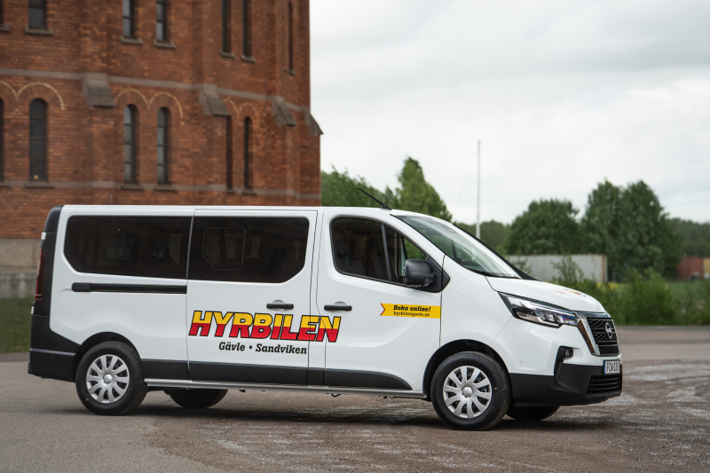 Hyrbilens minibuss åkandes på grusplan.